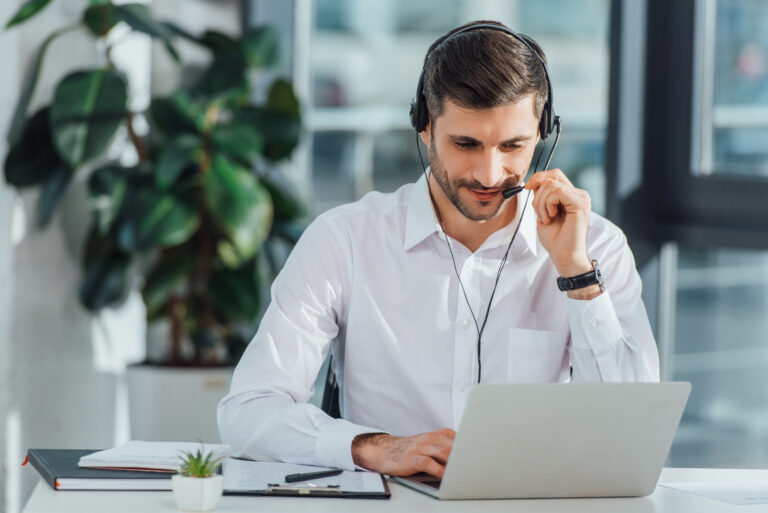Smiling support professional wearing a headset and working on a laptop