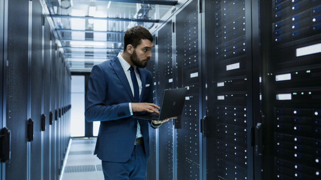 IT engineer stands in front of server rack cabinet managing secure cloud hosting inside a protected data center